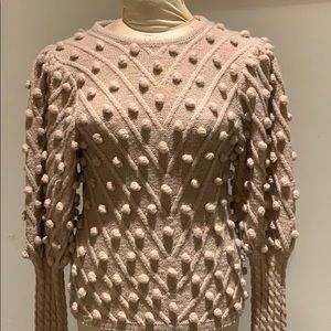 Pink pompom shirt with puffed sleeves.